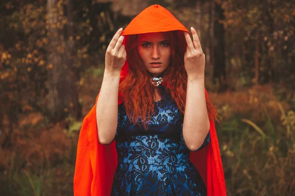 Pretty Red Riding Hood Woman is going on autumn forest road. — Stock Photo, Image