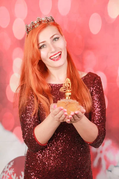 Menina ruiva bonita com lantejoulas vermelhas vestido mantém frasco de perfume e feliz — Fotografia de Stock