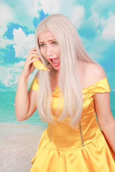 Divertido triste chica infeliz con teléfono de plátano sobre fondo azul . — Foto de Stock