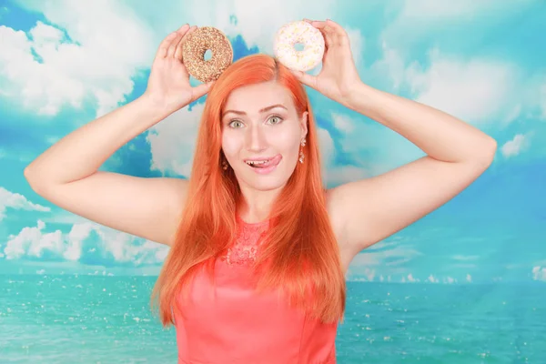 Primer plano retrato de una chica guapa satisfecha comiendo rosquillas sobre fondo azul — Foto de Stock