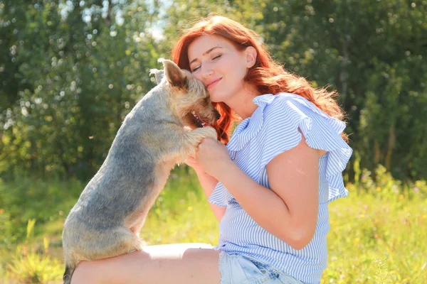 Glad söt ung kvinna sittande och kramas sin hund på naturen — Stockfoto