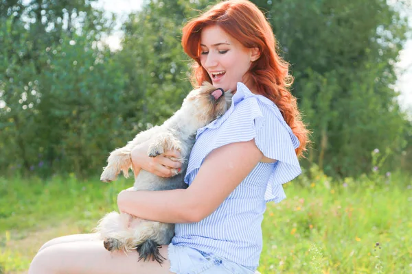 Веселая красивая молодая женщина сидит и обнимает свою собаку на природе — стоковое фото