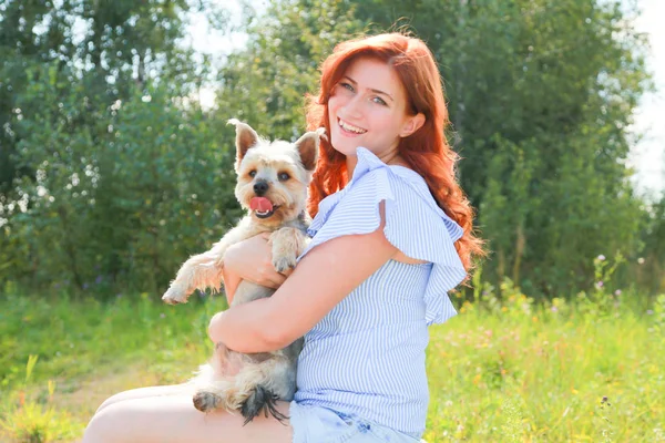 Весела красива молода жінка сидить і обіймає свого собаку на природі — стокове фото