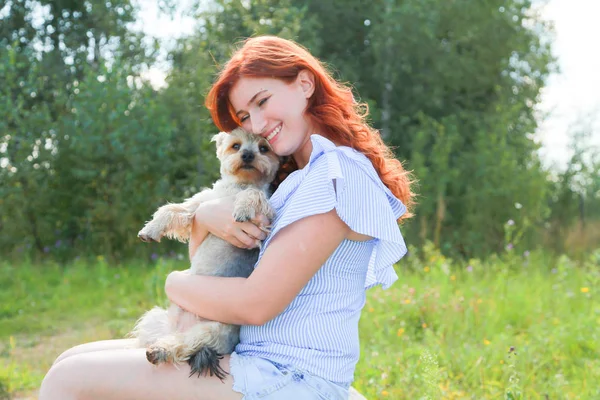 Fröhliche hübsche junge Frau sitzt und umarmt ihren Hund in der Natur — Stockfoto