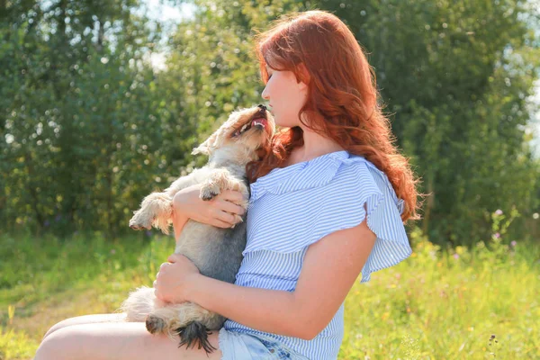 Cheerful pretty young woman sitting and hugging her dog on the nature — Stock Photo, Image