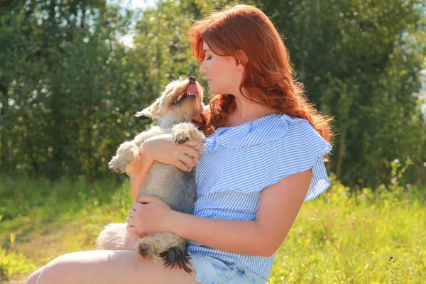 Fröhliche hübsche junge Frau sitzt und umarmt ihren Hund in der Natur — Stockfoto