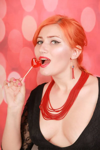 ロリポップを食べて驚いたセクシーな女の子。ハート型赤い甘い美しさグラマーモデル女性. — ストック写真