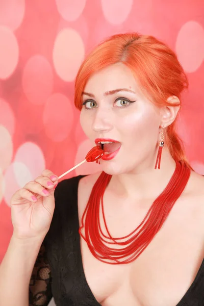 Chica sexy sorprendida comiendo piruleta. Belleza Glamour Modelo mujer con forma de corazón rojo dulce . — Foto de Stock