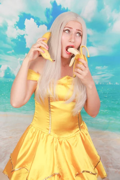 파란색 배경에 핀 업 노란색 드레스에 예쁜 소녀입니다. 바나나 다이어트. — 스톡 사진