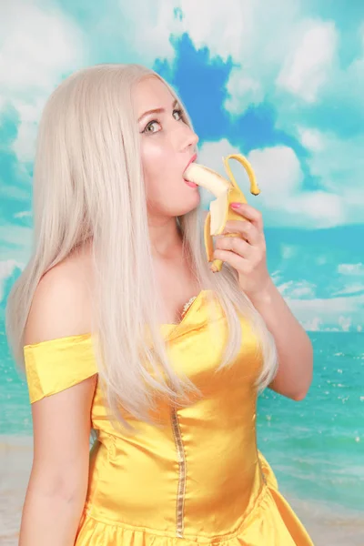 Mooi meisje in Pinup gele jurk op blauwe achtergrond. banaan dieet. — Stockfoto