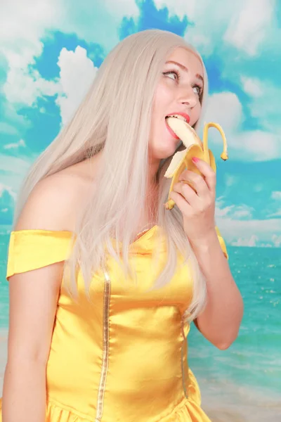 Mooi meisje in Pinup gele jurk op blauwe achtergrond. banaan dieet. — Stockfoto