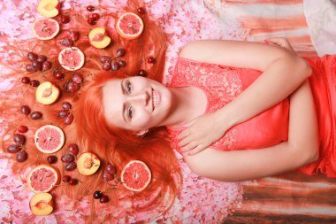 Güzel kadın pembe parlak arka plan üzerinde saçlarını etrafında meyve ile yalan