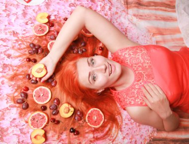 Güzel kadın pembe parlak arka plan üzerinde saçlarını etrafında meyve ile yalan