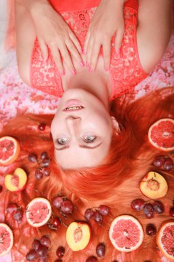 Güzel kadın pembe parlak arka plan üzerinde saçlarını etrafında meyve ile yalan