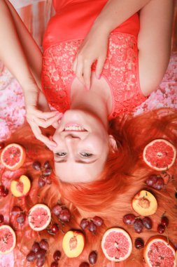 Güzel kadın pembe parlak arka plan üzerinde saçlarını etrafında meyve ile yalan