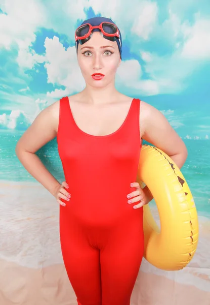 演播室拍摄美女性感女人穿红色复古泳衣，并携带生命戒指在蓝天背景 — 图库照片