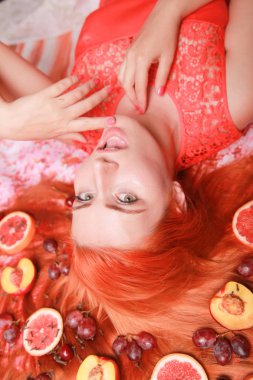 Güzel kadın pembe parlak arka plan üzerinde saçlarını etrafında meyve ile yalan