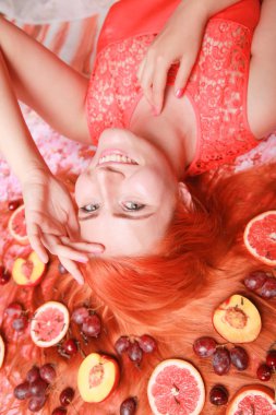Güzel kadın pembe parlak arka plan üzerinde saçlarını etrafında meyve ile yalan