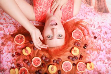 Güzel kadın pembe parlak arka plan üzerinde saçlarını etrafında meyve ile yalan