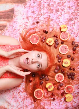 Güzel kadın pembe parlak arka plan üzerinde saçlarını etrafında meyve ile yalan