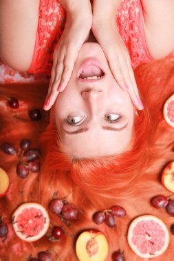 Güzel kadın pembe parlak arka plan üzerinde saçlarını etrafında meyve ile yalan