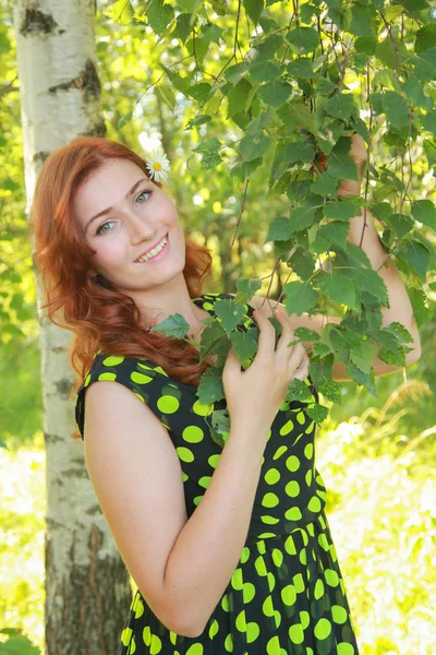 Schöne Mädchen geht mit Kamillenblüte in sonnigem Sommertag. — Stockfoto