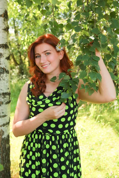 Schöne Mädchen geht mit Kamillenblüte in sonnigem Sommertag. — Stockfoto