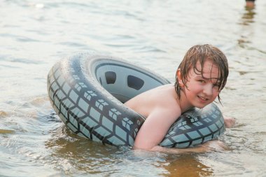 Sevimli küçük çocuk sıcak yaz gününde şişme yüzme halkası ile oynarken eğleniyor.