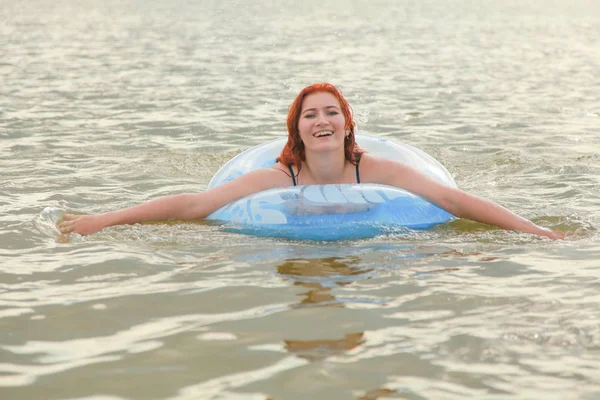 Рыжеволосая женщина, купающаяся в озере с голубым спасательным кругом — стоковое фото