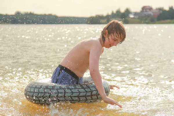 Милый мальчик веселится, играя с надувным плавательным кольцом в жаркий летний день . — стоковое фото