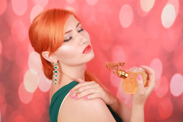 Saúde e beleza conceito de mulher segurando nas mãos perfume amarelo no fundo xmas vermelho — Fotografia de Stock