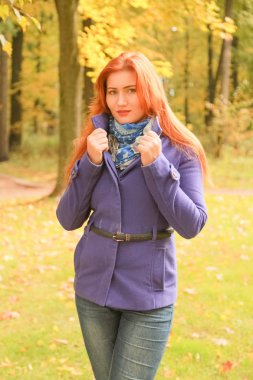 kırmızı saçlı mor ceket giyen genç güzel beyaz kadın ve sonbahar parkı yürüyor