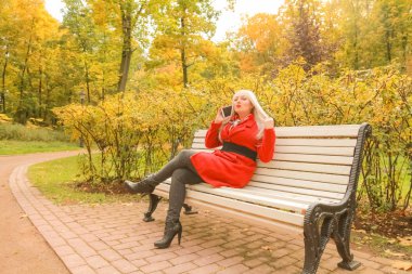 sonbahar parkta akıllı telefon ile genç güzel artı boyutu kafkas kadın