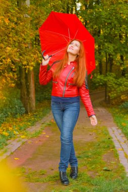 genç güzel artı boyutu kafkas kadın sonbahar parkta kırmızı şemsiye ile yürüyor