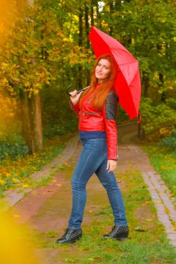 genç güzel artı boyutu kafkas kadın sonbahar parkta kırmızı şemsiye ile yürüyor