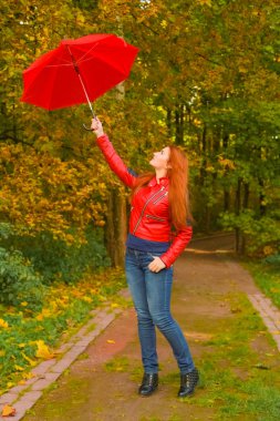 genç güzel artı boyutu kafkas kadın sonbahar parkta kırmızı şemsiye ile yürüyor