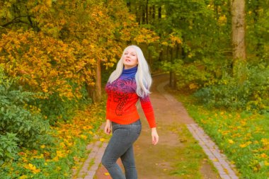 turuncu moda kazak genç güzel artı boyutu beyaz kadın sonbahar parkta yürüyor