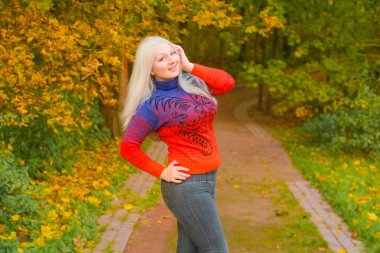 turuncu moda kazak genç güzel artı boyutu beyaz kadın sonbahar parkta yürüyor