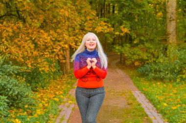 turuncu moda kazak genç güzel artı boyutu beyaz kadın sonbahar parkta yürüyor