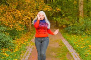 turuncu moda kazak genç güzel artı boyutu beyaz kadın sonbahar parkta yürüyor