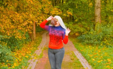 turuncu moda kazak genç güzel artı boyutu beyaz kadın sonbahar parkta yürüyor