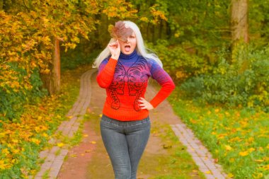 turuncu moda kazak genç güzel artı boyutu beyaz kadın sonbahar parkta yürüyor