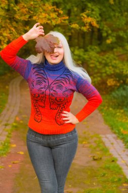 turuncu moda kazak genç güzel artı boyutu beyaz kadın sonbahar parkta yürüyor