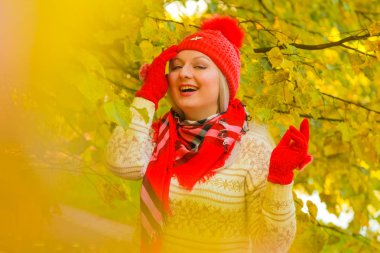 genç güzel artı büyük beyaz kadın pompom ve örme eldiven ile kırmızı şapkalı sonbahar parkta yürüyor