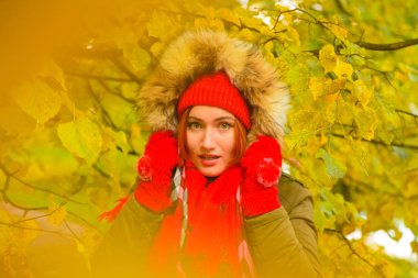 genç güzel artı büyük beyaz kadın pompom ve örme eldiven ile kırmızı şapkalı sonbahar parkta yürüyor