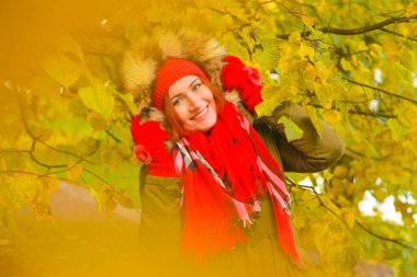 genç güzel artı büyük beyaz kadın pompom ve örme eldiven ile kırmızı şapkalı sonbahar parkta yürüyor