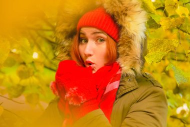 genç güzel artı büyük beyaz kadın pompom ve örme eldiven ile kırmızı şapkalı sonbahar parkta yürüyor