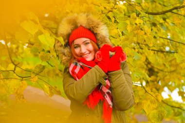 genç güzel artı büyük beyaz kadın pompom ve örme eldiven ile kırmızı şapkalı sonbahar parkta yürüyor