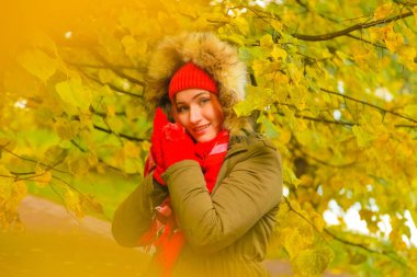 genç güzel artı büyük beyaz kadın pompom ve örme eldiven ile kırmızı şapkalı sonbahar parkta yürüyor