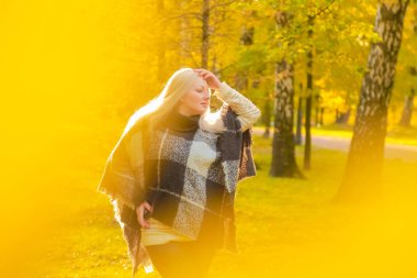 genç güzel artı boyutu kafkas kadın ekose yün poncho sonbahar parkta yürüyor